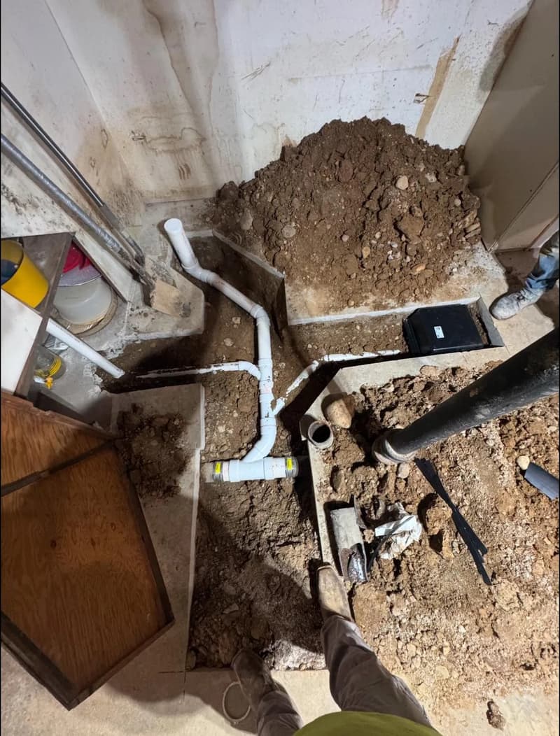 Excavated basement floor with new white drain piping