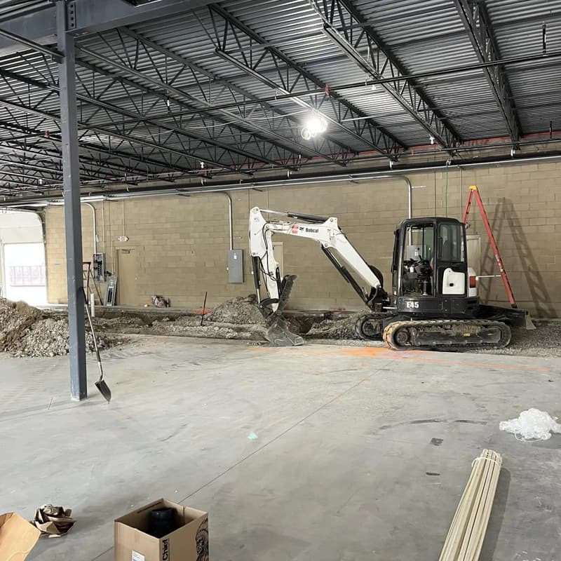Mini excavator digging inside an empty commercial building
