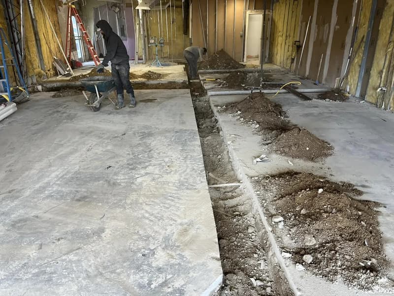 Crew trenching through a concrete floor indoors